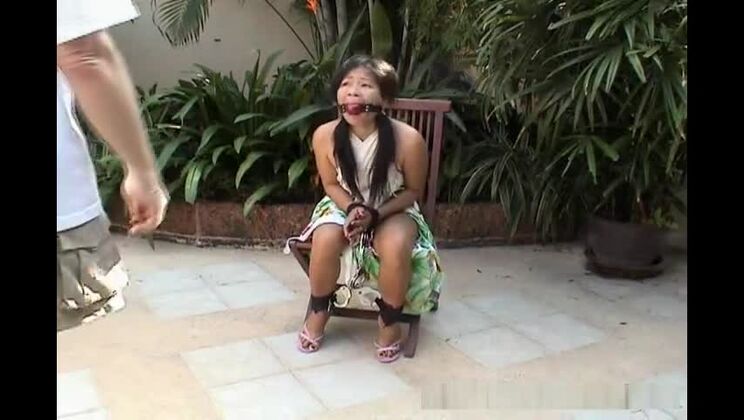 Una atractiva chica asiática atada a una silla.