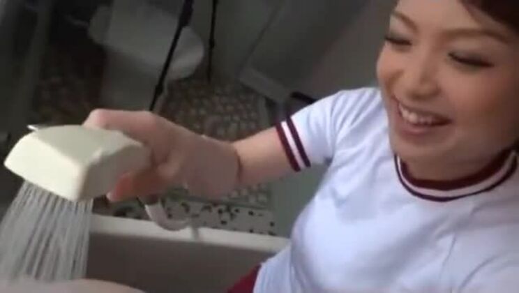 Una colegiala tetona con uniforme de entrenamiento es follada por detrás por un hombre mientras está de pie en la bañera.